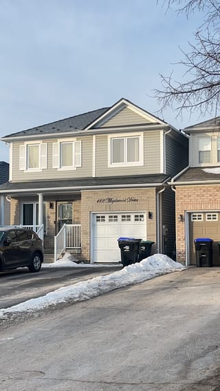 Two-storey suburban home at 142 Maplewood Drive, Angus ON, with black Interlock aluminum slate metal roofing on a medium-pitch gable, tan vinyl siding, and brick facade.
