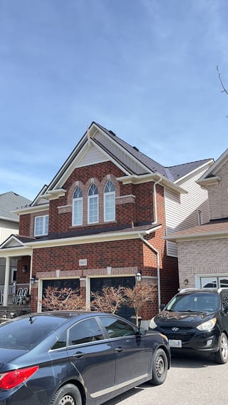 Two-storey red brick Colonial home in Oshawa with Interlock aluminum slate roof in Colonial Brown, featuring steep complex gables and arched upper windows.