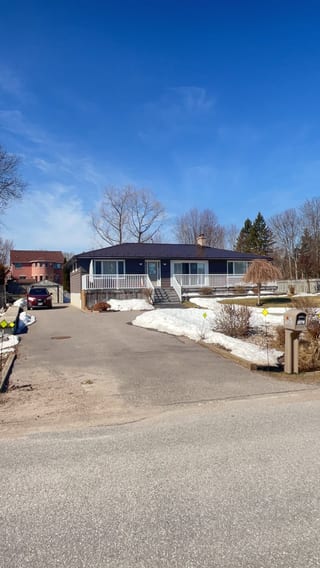 Single-storey ranch home in Innisfil ON with Interlock Colonial Brown aluminum slate metal roof, white front porch railing, and chimney, photographed in winter.