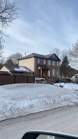 Two-storey brick Colonial home in Angus ON with Interlock Colonial Brown slate metal roof, multi-hip profile, viewed from street in winter.