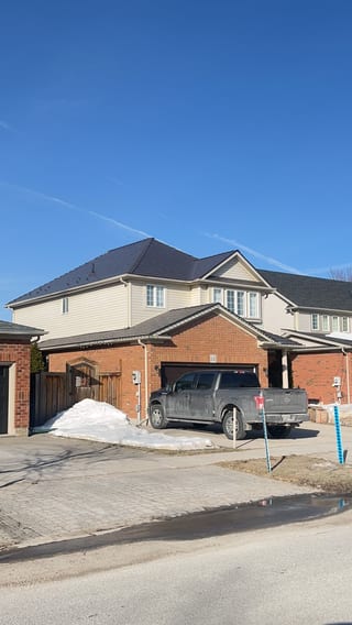 Two-storey brick home in Collingwood, ON with a complex hip roof clad in Interlock Tudor Brown aluminum slate roofing under a clear blue winter sky.