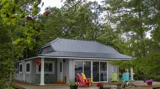 Deep Charcoal Interlock Cedar Shingle aluminum roof on a grey two-storey cottage with a large porch among tall, Winderemere, Ontario