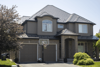 Two-storey suburban home in Guelph ON with complex multi-hip Interlock Tudor Brown aluminum slate metal roofing featuring a central dormer and stone facade.