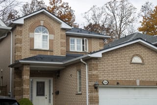Deep Charcoal Interlock Cedar Shingle aluminum roof on a beige two-storey colonial home with dormers among tall, Mississauga, Ontario