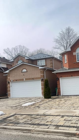 Black Interlock Slate aluminum roof on a two-storey red brick home with white trim among suburban, Mississauga, Ontario