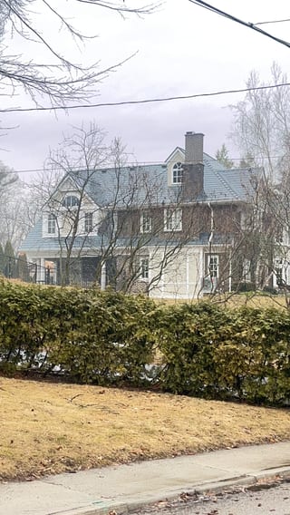 Two-storey colonial brick home in Burlington ON with steep deep charcoal Interlock aluminum slate roof, twin dormers, and brick chimney, viewed from street.