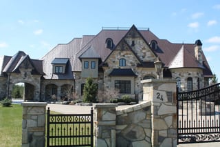 Colonial Brown Interlock Slate aluminum roof on a two-storey stone home with dormers in a rural setting, Caledon, Ontario