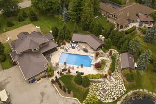 Aerial view of a large Craftsman-style home in Bradford, ON featuring Interlock Tudor Brown aluminum slate metal roofing with complex multi-hip roof and poolside estate.