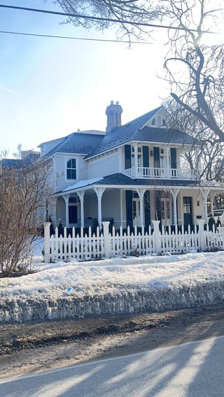 Victorian two-storey home in Collingwood ON with deep charcoal Interlock aluminum slate roof, wrap-around porch, white picket fence, and chimney in winter.