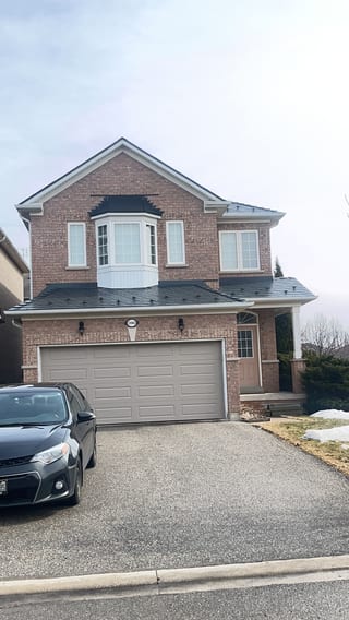 Two-storey brick home in Mississauga with Interlock deep charcoal aluminum slate metal roofing covering a multi-plane complex roof with bay window.