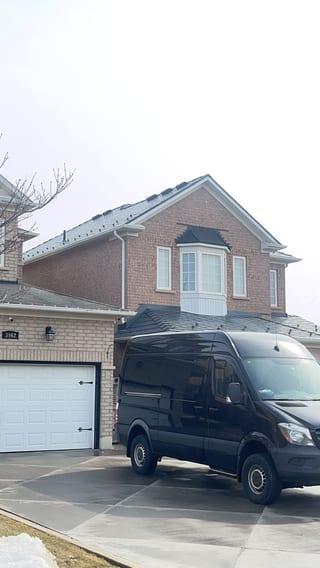 Two-storey brick home in Mississauga with Interlock deep charcoal aluminum slate metal roof featuring a front dormer and complex hip-gable profile.