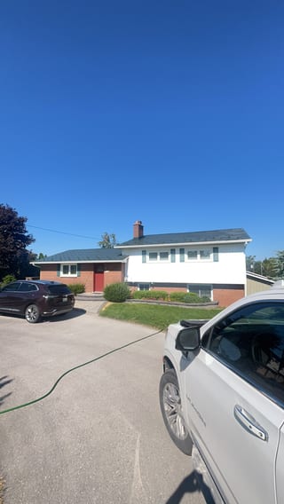 Hunter green Interlock aluminum shingle roof on a 1.5-storey brick ranch home in Beaverton, ON, with brick facade and red front door.