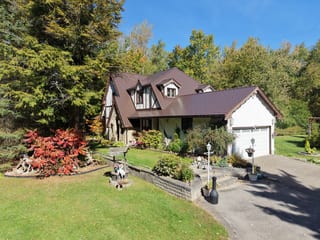Colonial Brown Interlock Slate aluminum roof on a colonial two-storey home with dormers among tall trees, Fraserville, Ontario