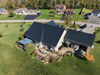 Black Interlock Slate aluminum roof on a single-storey home with a dark roof in a forested rural, Kawartha Lakes, Ontario