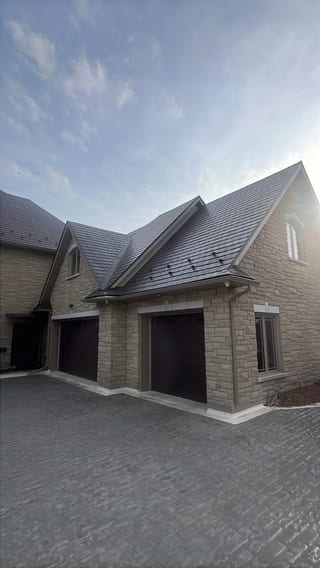 Tudor Brown Interlock Slate aluminum roof on a brown Tudor style home with stone facade in a rural, Sudbury, Ontario