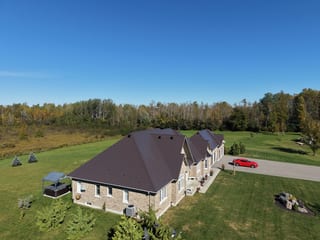 Tudor Brown Interlock Slate aluminum roof on a brown single-storey home with dormers in a forest clearing, Kawartha Lakes, Ontario