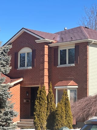 Aged Copper Interlock Shingle aluminum roof on a red brick two-storey home with dormers among tall pines, Orléans, Ontario