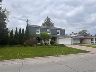 Two-storey colonial-style home in Ottawa with Interlock charcoal grey aluminum shingle roof, chimney, brick lower facade, and double garage.