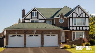 Tudor-style brick home in Nepean, ON with hunter green Interlock aluminum shingle roof, three-car garage, and decorative half-timbering.