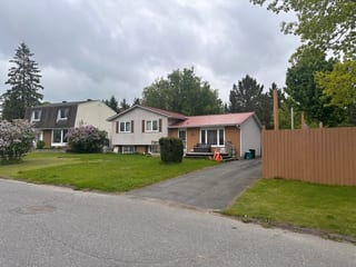 Street view of a 1.5-storey ranch-style home in Munster, ON featuring a Tile Red Interlock aluminum shingle metal roof with a simple gable profile.
