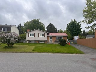 Street view of a split-level ranch home in Munster, ON featuring a tile-red Interlock aluminum shingle roof with brick chimney, surrounded by mature trees.