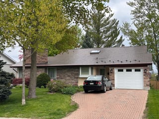 Single-storey ranch home in Ottawa with a low-pitch Colonial Brown Interlock aluminum shingle roof, stone facade, skylight, and chimney.