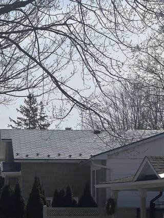 Charcoal Grey Interlock Shingle aluminum roof on a white single-family home with a gable roof in a suburban, Gloucester, Ontario