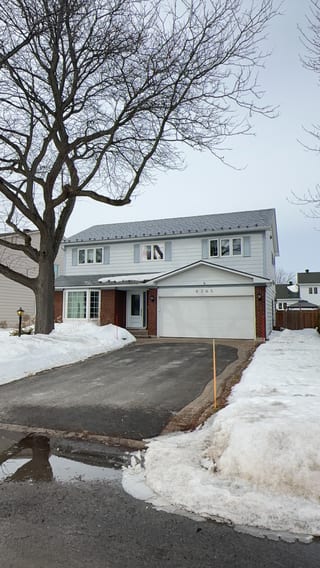 Two-storey colonial-style home in Orleans ON with Interlock charcoal grey aluminum slate metal roofing, brick lower facade, and attached garage.