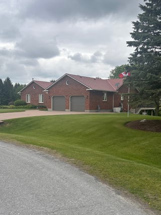 Single-storey brick ranch home in North Gower ON with Interlock Tile Red aluminum shingle roof, two-car garage, and manicured lawn.