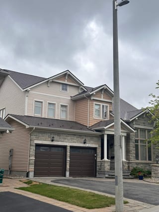 Two-storey Craftsman home at 285 with Interlock Tudor Brown aluminum slate roofing, multi-plane gabled roof, stone facade, and double garage.