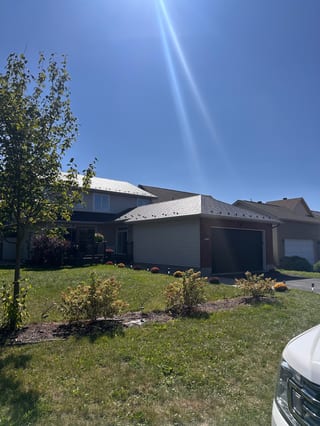 Two-storey suburban home with Interlock black aluminum slate metal roofing across multi-hip profiles, brick and vinyl siding, Ottawa ON.
