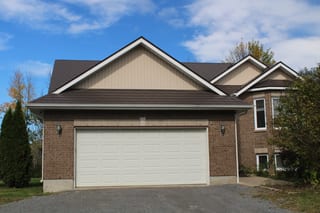Tudor Brown Interlock Slate aluminum roof on a brown two-storey Tudor home with dormers in a rural, Kingston, Ontario