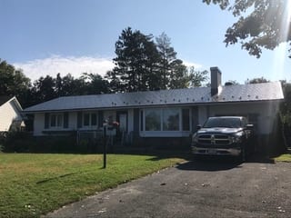 Single-storey ranch home in Ottawa with a low-pitch deep charcoal Interlock aluminum slate metal roof, chimney, and attached garage.