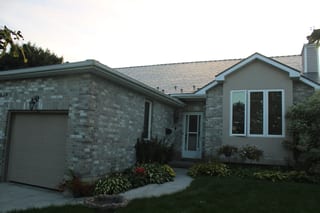 Deep Charcoal Interlock Cedar Shingle aluminum roof on a tan one-storey home with a metal roof among trees, Kingston, Ontario