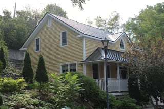 Black Interlock Slate aluminum roof on a two-storey yellow home with dormers in an urban forest, Kingston, Ontario