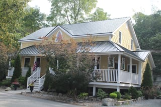 Black Interlock Slate aluminum roof on a two-storey home with a metal roof among tall trees, Kingston, Ontario
