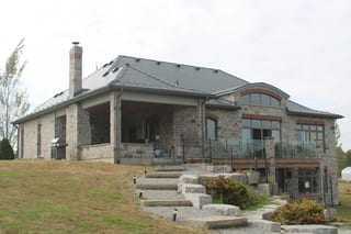 Deep Charcoal Interlock Slate aluminum roof on a modern home with a stone facade on a rural property, Picton, Ontario