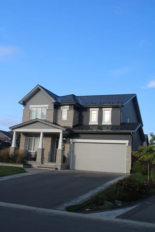 Black Interlock Slate aluminum roof on a grey two-storey home with a metal roof and dormers among, Carleton Place, Ontario