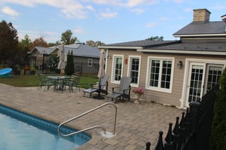 Deep Charcoal Interlock Slate aluminum roof on a tan home with a metal roof among tall trees, Carleton Place, Ontario