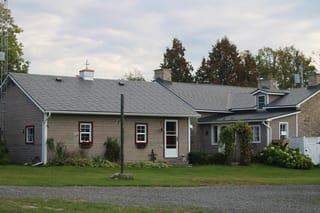 Deep Charcoal Interlock Slate aluminum roof on a cottage with a grey roof among tall trees, Carleton Place, Ontario