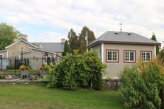 Deep Charcoal Interlock Slate aluminum roof on a beige home with a metal roof and two windows among tall, Carleton Place, Ontario