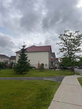 Street view of a two-storey suburban home in Ottawa with Interlock aluminum slate roofing in Tile Red, viewed from across a sidewalk.