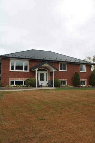Black Interlock Slate aluminum roof on a red brick home with a metal roof in a suburban rural area, Carrying Place, Ontario