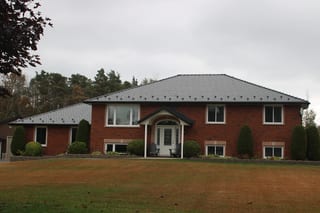 Black Interlock Slate aluminum roof on a red brick two-storey home with a metal roof in a forest, Carrying Place, Ontario