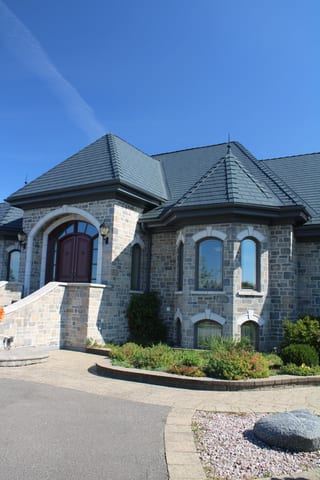 Deep Charcoal Interlock Slate aluminum roof on a grey stone house with a slate roof in a suburban, Alexandria, Ontario