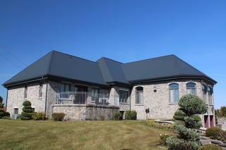 Deep Charcoal Interlock Slate aluminum roof on a modern home with a stone facade and black roof in a rural, Alexandria, Ontario
