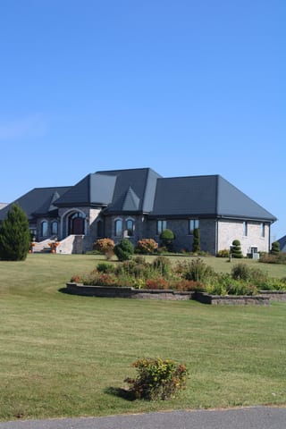 Deep Charcoal Interlock Slate aluminum roof on a two-storey home with stone facade and metal roof in a, Alexandria, Ontario