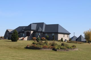 Deep Charcoal Interlock Slate aluminum roof on a single-storey home with a grey metal roof among tall trees, Alexandria, Ontario
