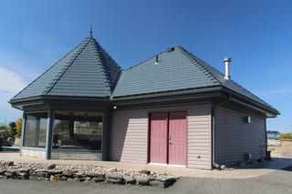 Deep Charcoal Interlock Slate aluminum roof on a tan single-storey modern home with a red door in a rural, Alexandria, Ontario