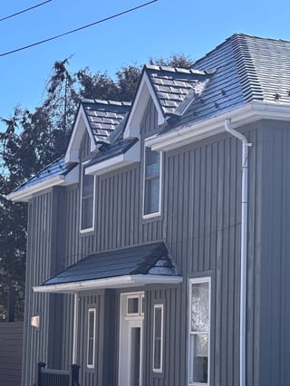 Black Interlock Slate aluminum roof on a grey two-storey colonial home with dormers in a suburban, Prince Edward, Ontario